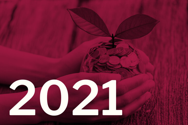 Die Zahl 2021, im Hintergrund eine Pflanze, die aus einem Glas mit Münzen wächst