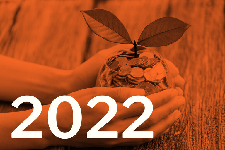 Die Zahl 2022, im Hintergrund eine Pflanze, die aus einem Glas mit Münzen wächst