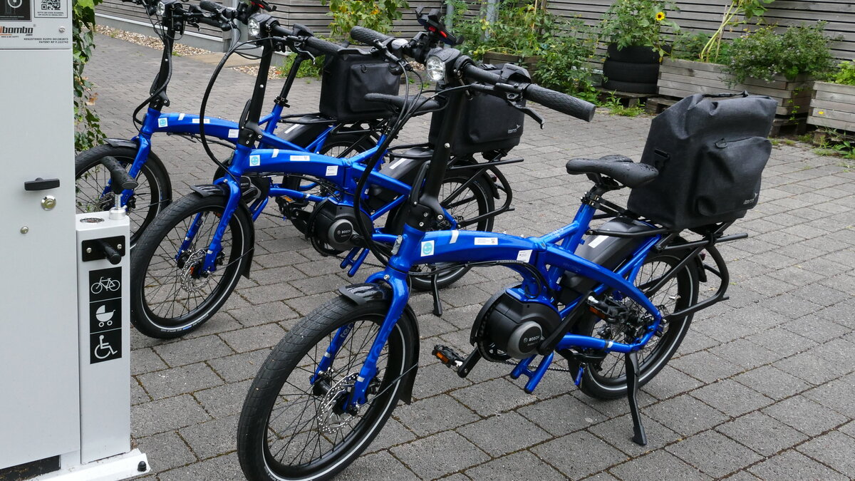 Drei Dienstfahrräder stehen neben einer Fahrradreparaturstation.
