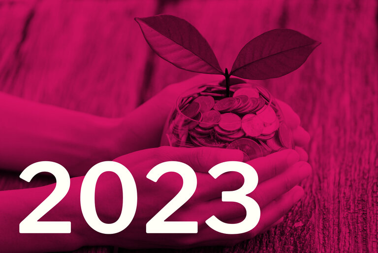 Die Zahl 2023, im Hintergrund eine Pflanze, die aus einem Glas mit Münzen wächst